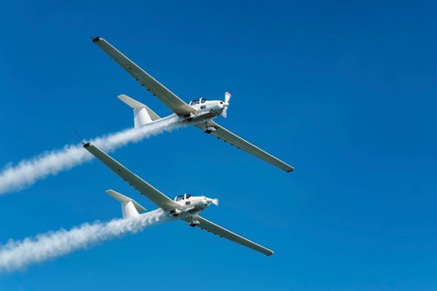 Stunt aerobatic plane performing stunts in blue sky with smoke trail. Concept of teamwork,
