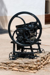 Historische Metallmaschine mit großen Rädern auf steinigem Untergrund vor einem historischen