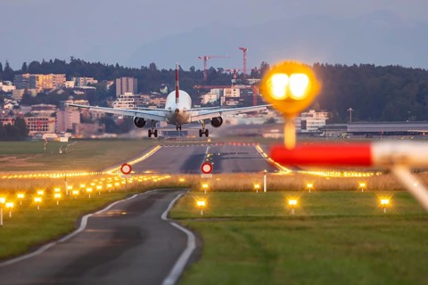 Aircraft of the airline Swiss landing in the evening with illuminated runway. Zurich Airport,