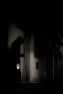 Old man with hood, stick and lantern in gloomy city neighbourhood, Mindelheim, Unterallgäu,