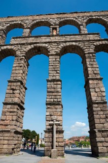 A majestic ancient aqueduct under a clear blue sky, with detailed stone arches, Aqueduct, Segovia,
