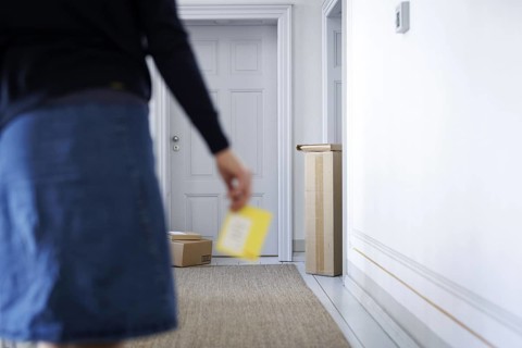A woman walks through a stairwell in Berlin with a parcel collection note, 08/08/2024