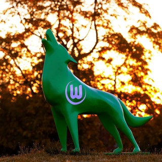 Green wolf sculpture with VfL Wolfsburg logo at sunset, Wolfsburg, Lower Saxony, Germany, Europe