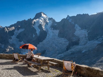 Mountain hut Cabane de l'A Neuve, tourists sitting on terrace, Aiguille Rouges du Dolent massif at