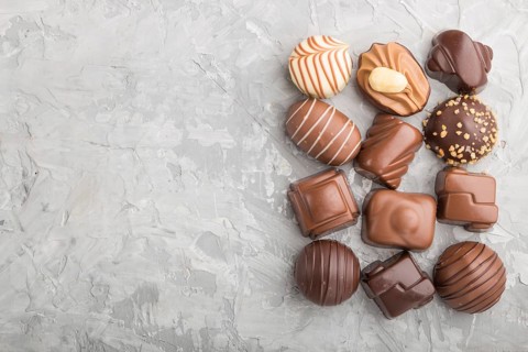 Different chocolate candies on a gray concrete background. top view, flat lay, copy space