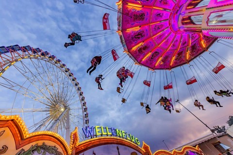 Chain carousel and Ferris wheel in the evening. 177th Cannstatter Volksfest at the Cannstatter