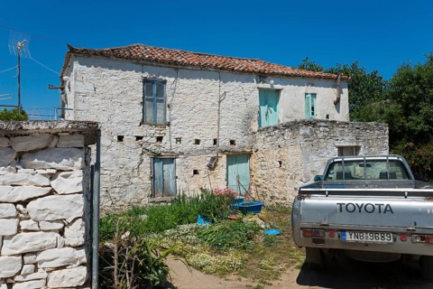 Old stone house with a Toyota pickup truck in the foreground in a rural setting, Taktikoupolis,