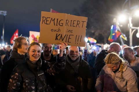 Participants with sign Remigrate yourselves to your knees!!! at the demonstration under the motto