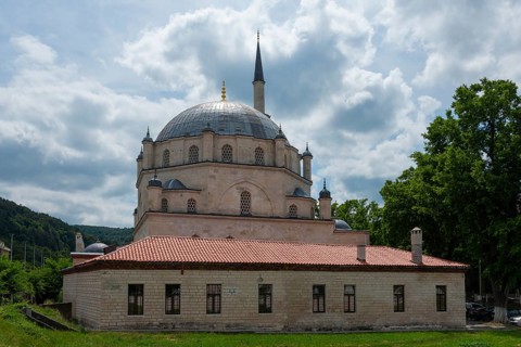 View of a mosque with dome and minaret, flanked by trees under a cloudy sky, Tombul Mosque, Sherif
