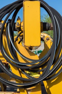 Coiled black rubber hose on yellow heavy machinery in junkyard, Quebec, Canada, North America