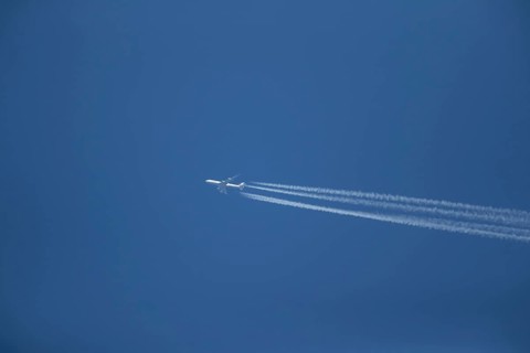 Boeing 747 aircraft of Lufthansa airlines flying across a blue sky leaving a contrail or vapor