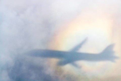An aeroplane casts a shadow on a cloud, silhouette, halo rainbow. Germany