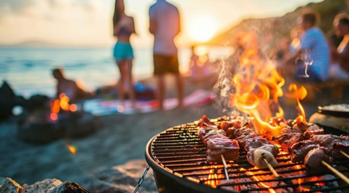 Barbecue BBQ family picnic party on the beach with skewers of meat and meat steaks over charcoal,