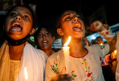 Students holds candle and shout slogans as they participate in a protest against the rape and