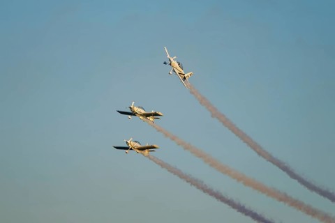 Three stunt aerobatic planes performing stunts in blue sky with smoke trail. Concept of teamwork,