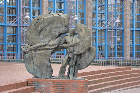 Sculpture Man in a circle by Eberhard Linke 1988, male figure with long outstretched arm, bronze