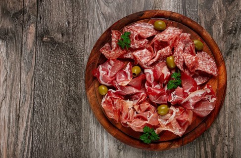 Assortment, sliced meat appetizer, prosciutto, salami and ham, with olives, on a wooden board,