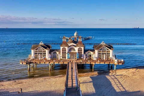 Symmetrical view of the pier with historic building above the blue sea and sand, Rügen, Sellin