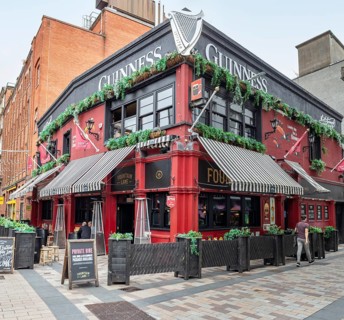 A traditionally styled pub with a red façade and green plants on the outside, Belfast