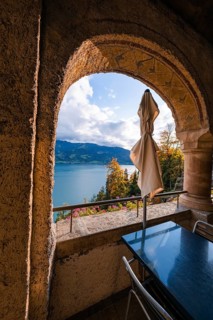 Looking through a stone arch onto a lake with mountains in the background, peaceful atmosphere,