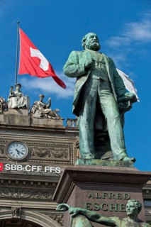 Swiss flag behind monument to Alfred Escher, Swiss politician, business leader and railway pioneer,