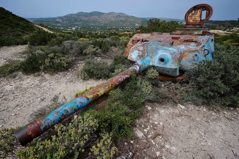 A rusty tank lies in a green landscape, surrounded by bushes, Anthony Quinn Bay, Vagies Bay,