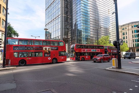City scene with several red double-decker buses and modern skyscrapers in London, United Kingdom