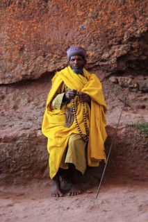 Rock churches of Lalibela, pilgrim prays with a rosary in front of a rock church, Ethiopia, Africa