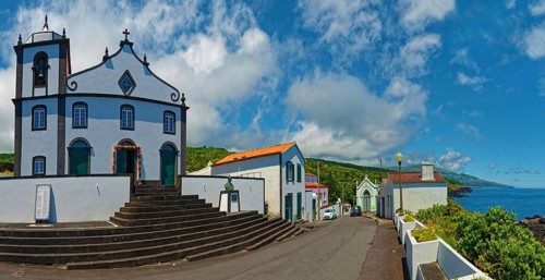 White church Igreja de São João Baptista on the village square in coastal location with clear sky