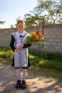 Schoolgirl with a bouquet of flowers on her first day at school, Issyk-Kul region, Kyrgyzstan, Asia