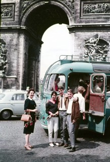 Three young people two men a woman standing by open bus door entrance older woman nearby, Arc de