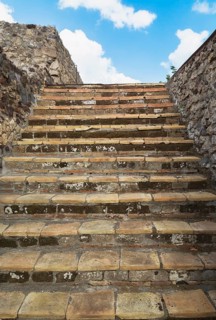 Close-up of old stairs with steps made of terracotta stone tiles and bordered by stone walls at the