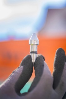 Metal component in gloved hand outdoors, Wend Glasfasermontage during jetting of conduits for fibre