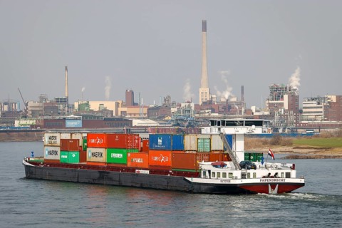 Krefeld, North Rhine-Westphalia, Germany - Cargo ship sails on the Rhine past the chemical plant