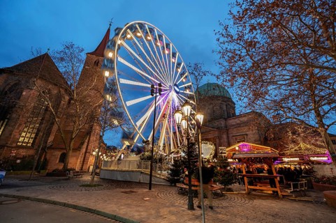 Ferris wheel at the winter village, Christmas market at dusk, St James' Church on the left, St