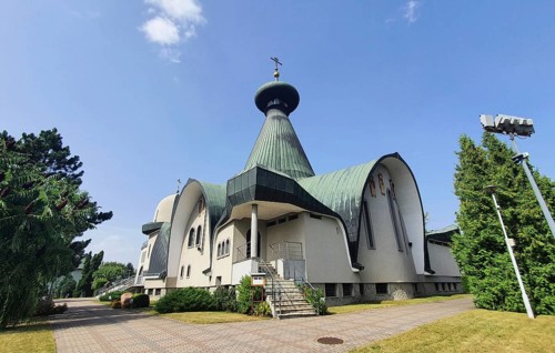 White modern church with green roof and cross against blue sky, Cathedral of the Holy Trinity,