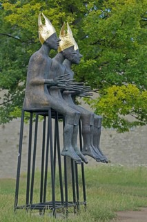 Sculpture Enthroned by Volkmar Kühn 2021, three bishops with golden mitres sitting on stools, row,