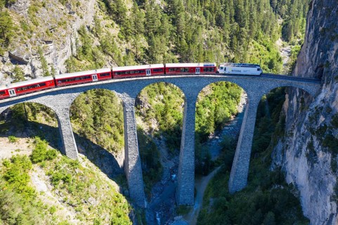 Drone shot of train passing the Landwasserviadukt near Filisur, red train of Bernina Express,
