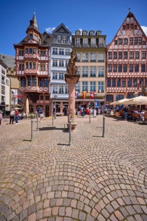Minerva fountain with half-timbered houses on the Römerberg town hall square under a blue sky with