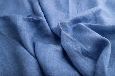 Fragment of blue linen tissue. Side view, natural textile background and texture. wave concept,