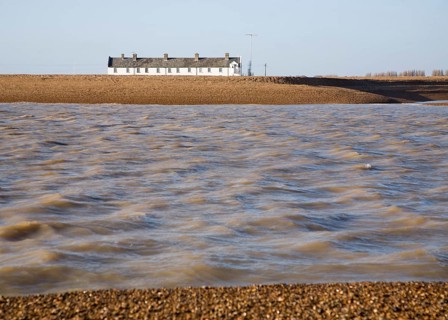 White terrace of Coastguard Cottages, beach and sea viewed from offshore, Shingle Street, Suffolk,