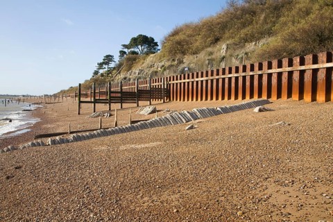 Rusty steel piling sea wall defences and shingle beach near Bawdsey Quay, Suffolk, England, United