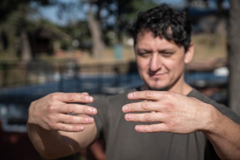 A middle-aged Caucasian man assumes the static posture of Tree Hugging, an essential technique in