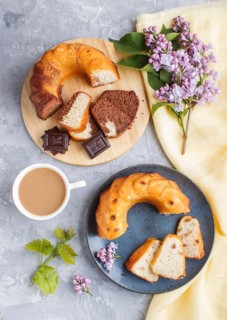 Cakes with raisins and chocolate and a cup of coffee. lilac flowers on a gray concrete background,