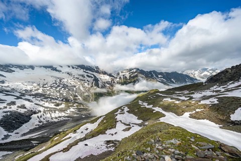 Mountain landscape with snow fields and high fog in the valley, summit Hoher Weißzint and