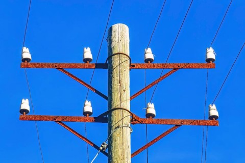 Old telephone pole with white porcelain insulators against a blue sky, Sweden, Europe