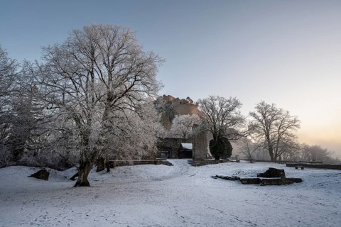 The snow-covered Karlsbastion of the Hohentwiel fortress ruins in front of sunrise on a cold winter