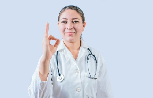 Beautiful female doctor gesturing approval isolated. Smiling female doctor approving and