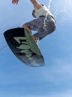 Young man jumping and flying with wakeboard, water sports and water skiing in the wakepark