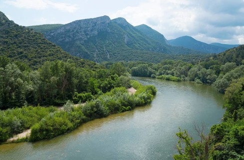 Wide view over a river flowing through a densely forested and mountainous landscape, River Nestos